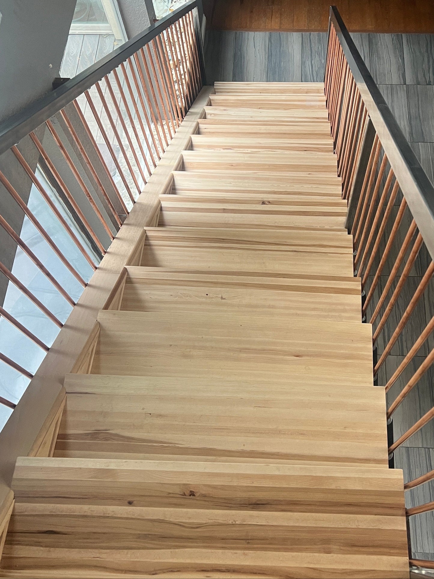 Hickory floating staircase with glass balustrade in a modern interior setting