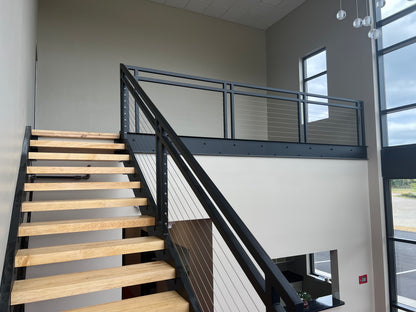 Light hardwood floating stair treads on a black metal open-riser staircase in an industrial interior