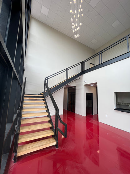 Light hardwood floating stair treads on a black metal open-riser staircase above a red floor